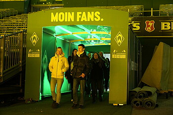 Fans kommen aus dem Spielertunnel, gelbliches Licht.