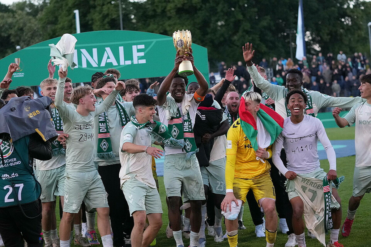 Die Mannschaft feiert mit dem Pokal. 
