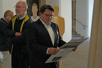 Dr. Hubertus Hess-Grunewald schaut sich eine Zeitung innerhalb der Ausstellung an.