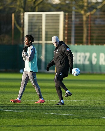 Ole Werner mit grauer Mütze, Winterjacke und Ball am Fuß auf dem Trainingsplatz