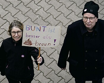 Zwei Menschen halten ein Plakat.