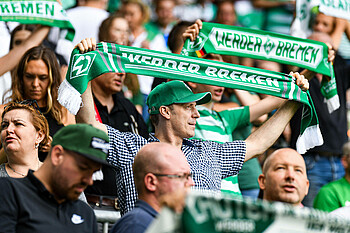 Ein Fan hält einen Werder-Schal in Höhe.