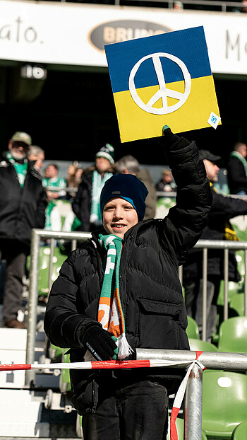 Ein Fan hält im Stadion die Ukraine-Flagge mit dem Peace-Zeichen drauf hoch (Foto: W.DE). 